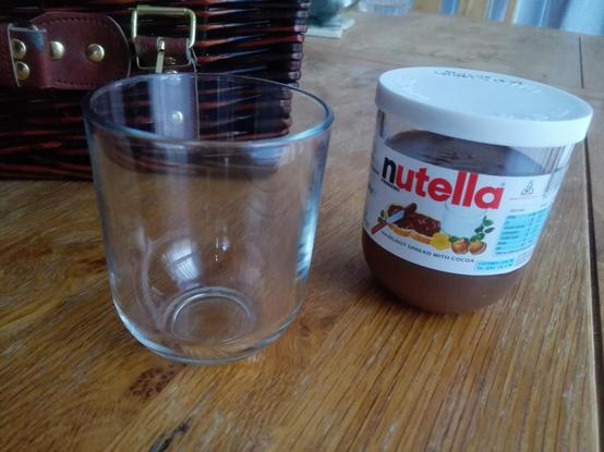 Image of a small glass and next to it is a small jar of Nutella. It is clear that the glass comes from the Nutella jar of the same shape.