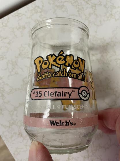 A small clear glass with the Pokémon logo and the words “Gotta catch ‘em all!” below it. In a pink elongated oval with a pink and white pokéball on the right side are the words “#35 Clefairy tm”.

Below that in white type is “Collect all 9 fun scenes” and at the bottom in a pink band, the Welch’s logo.