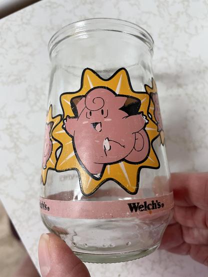 A mildly scuffed up picture of a kicking Clefairy which looks like it’s bursting out of a yellow starburst background. The edges of two small Clefairy pictures are visible on the sides. At the bottom, the same Welch’s logo in the pink band.