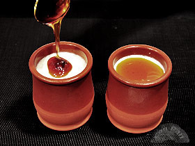 Two ceramic cuajada pots, one with a spoon of honey being added.