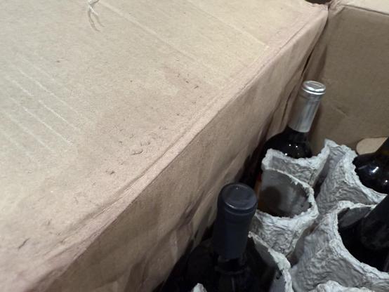 Photo of the inside of the box showing the wine stained cardboard and the space where the missing, presumably broken, bottle once sat. (The top layer of the protection that usually does a great job preventing these bottles from harm was removed to see which bottle was missing.)