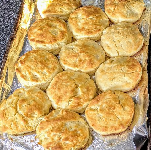 Half sheet tray of cooked biscuits that look golden brown and delicious.