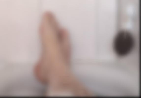 A very blurry picture of some hairy legs in a bathtub.