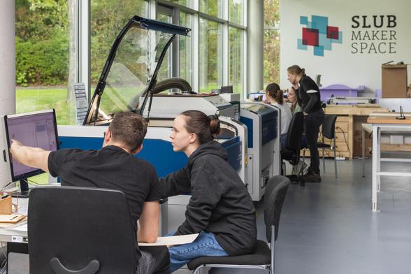 Im Makerspace, Personen an Bildschirmen und Geräten im Gespräch.