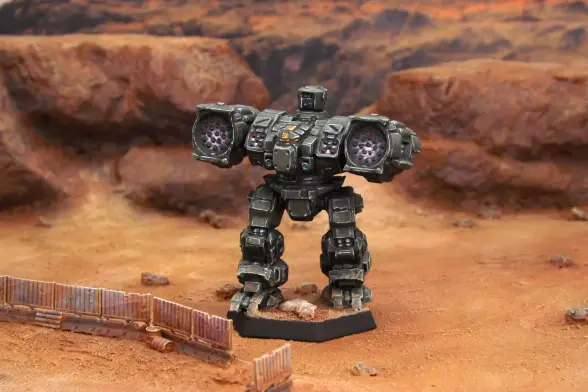 A painted miniature of a Longbow 'Mech.  It is olive drab and the cockpit glass is orange.  The miniature is photographed on desert terrain.