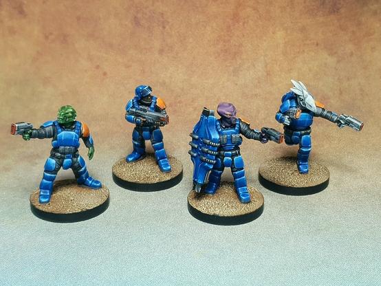A photo of 4 painted sci-fi miniatures. Sci-fi soldiers in bright shiny blue armour