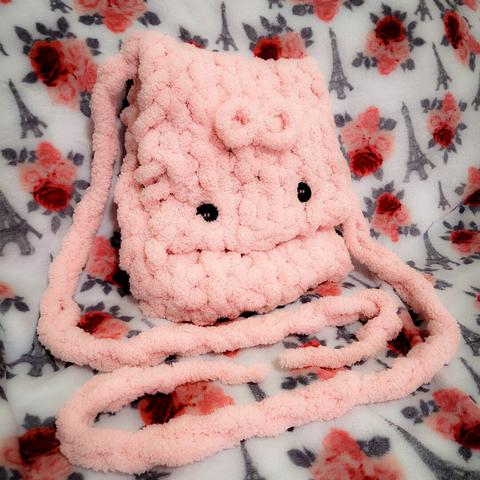 - white blanket with patterns: grey Eiffel Towers, red/pink roses with grey leaves
- soft pink fluffy crocheted pouch with a bow in the center and 2 black buttons
- two long strands are laid out in front