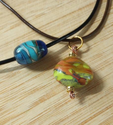 Lampwork glass pendant in earth tones and a large lampwork glass bead in shades of blue.