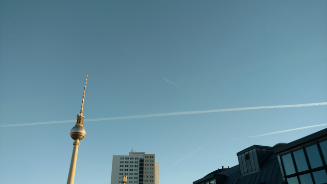 A flawless winter sky above Berlin. The Fernsehturm is visible, and some comtrails above the parts of houses that are visible in this bottom-up shot.