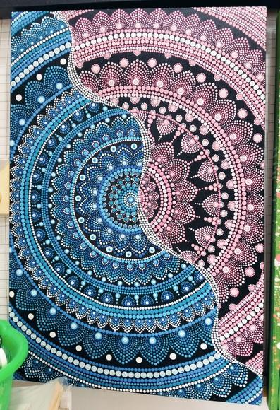 a mandala design, cropped at the sides, a wavy white line of dots running diagonally, half he mandala is blue, half pink