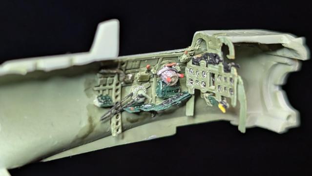 Inside of the left side of the fuselage of a 1 to 72 model kit for a zero with painted cockpit details including the forward instrument panel