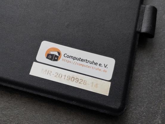 Foto der Ecke einer Hülle, auf der dein Computertruhe-Sticker und die Seriennummer "MR-20190928-14" kleben.