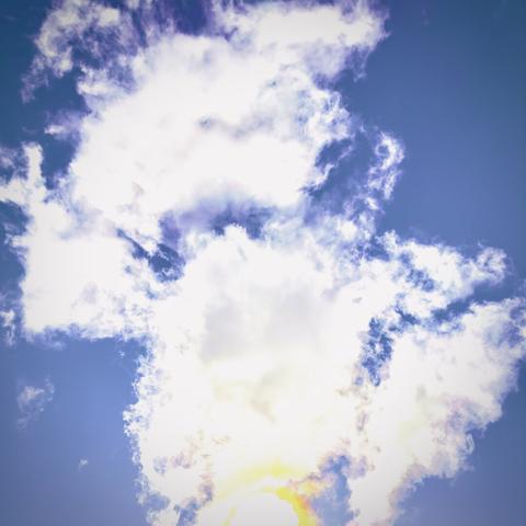 White clouds seem to burst out from the sun peaking through the bottom of the frame on a bright blue, clear day.