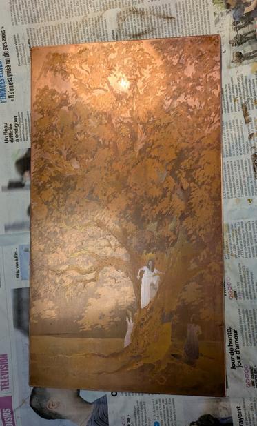 Photo of a copper plate, placed on scrap newspapers, etched with the image of a large tree and three girls at its bottom.
