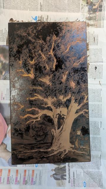 Photo of a copper plate, placed on scrap newspapers, mostly covered by etching ground. The parts not covered are depicting the main branches of a tree and some details of three characters standing in or near its trunk.