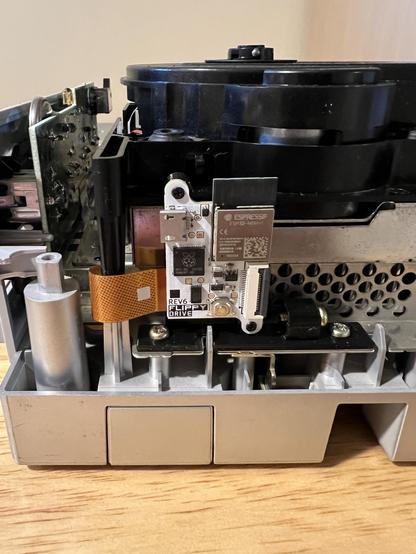 FlippyDrive modchip shown installed in its bracket, ribbon cable snaked in a gap between the heat shield and disk reader