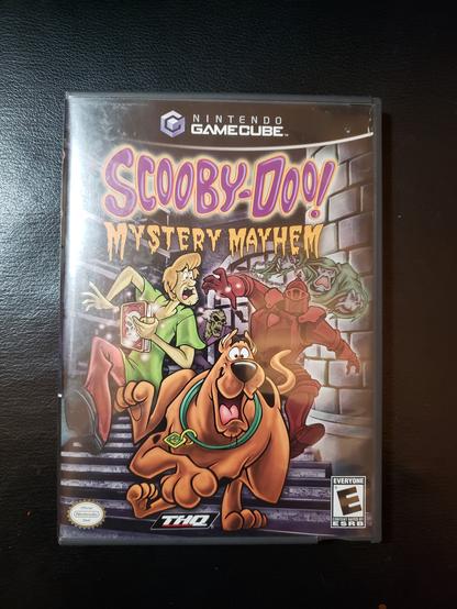 Scooby-Doo! Mystery Mayhem on the Nintendo GameCube... or the case, anyways. It was never in my collection until last week and it took some patience to get it to run until the first mystery was completed. That's when it crashed again, and I didn't get to save.

I'd say it looks good enough for what it is but it's through an AV to HDMI converter that instantly makes the image widescreen, so that might have skewed it a bit. But it looks good for what it is and when it was released. The gameplay is simple enough - you plays as Scooby and Shaggy. You obtain a Grimoire that can trap ghosts via Ghostbuster Trap style and use that to trap actual ghosts. Non-ghosts pretending can't get trapped. The game keeps the spirit of the original Scooby-Doo Where Are You? series, laugh track and everything. The controls are simple enough after a while, but movement is a bit... stiff, I guess you can call it.

I suspect this game came out before Shaggy was converted to Vegetarianism - longish story that I probably have wrong anyways. I think it was Shaggy's original voice actor agreeing to reenter the role if Shaggy was a Vegetarian. Don't quote me on that.