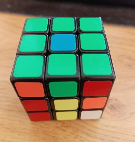 A seemingly innocent Rubik's cube (3x3). The top is all green apart from a blue center. However, the missing green square is on an edge and not a center piece, so it can never be moved to the center. This is because someone swapped the colour stickers around.