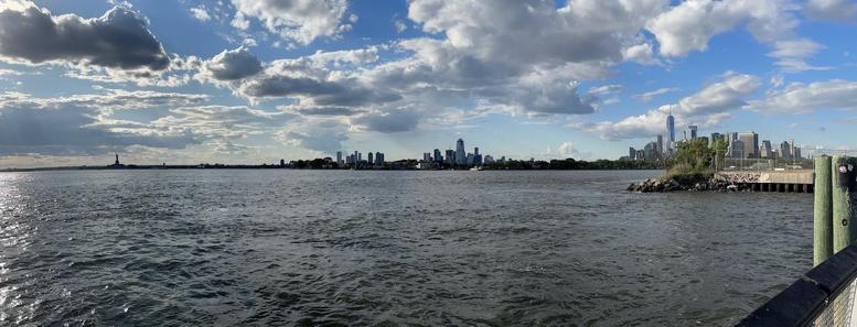 Panoramic photo of New York Harbor with the Statue of Liberty at left and Downtown Manhattan at right. The actual Red Hook is close by at right.