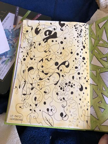 This photo shows a page in a sketch book. The entire page is coloured in a pale yellow with watercolour in an uneven manner. On top are sepia brown lines, some fine some thicker, going across the page in random ways. They curve and curl and cross another, some form shapes like leaves. Small spaces between lines that form rectangles or other closed shapes are coloured solid in brown. There are also circles coloured in brown.