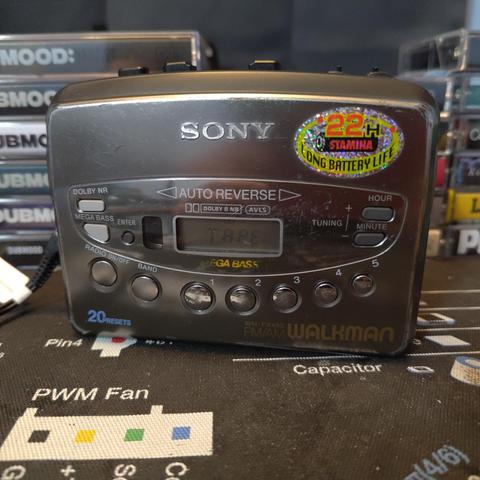 The Walkman at home and playing a cassette with headphones connected.