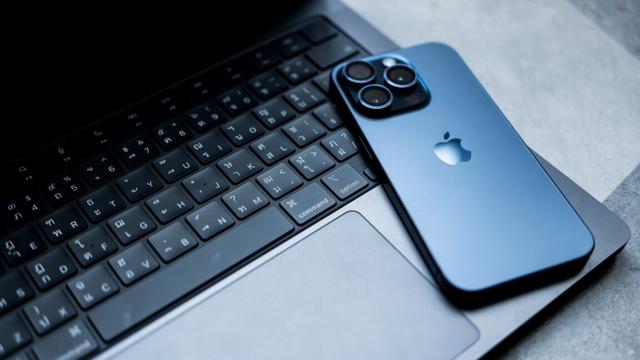 An iPhone lies face-down on top of a MacBook Pro.