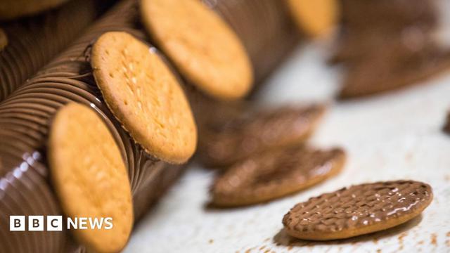 A layer of chocolate is applied to McVitie's Milk Chocolate Digestive biscuits on the production line at a McVitie's factory.