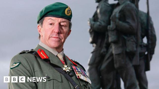 Gen Sir Gwyn Jenkins, in military uniform with medals on his chest, standing in front of the Commando Memorial in Locharber in the Scottish Highlands