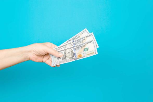 hand holding US dollars on blue background