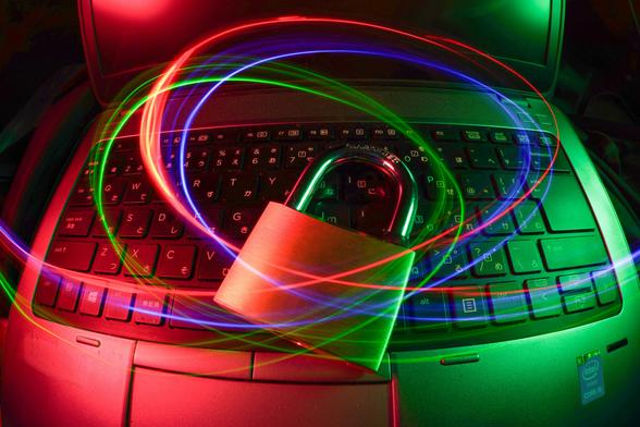 lila, rote und blaue Lichtillustrationen vor einem Laptop mit Vorhängeschloss