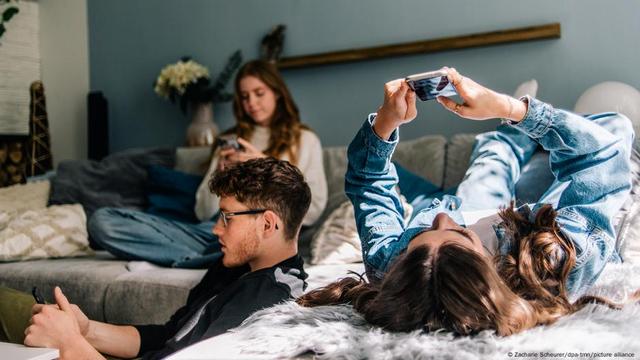 Three young people sit together and hold their smartphones