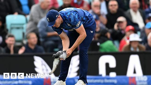 Matthew Potts of England picks up a pigeon on the cricket pitch