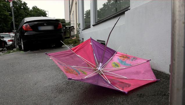 Ein Kinder-Regenschirm liegt auf der Straße  