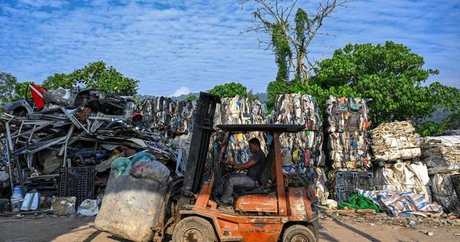 A worker uses a forklift to carry plastic waste before putting it into a compressor to recycle and sell it in Bentong, Malaysia's Pahang state, on June 25, 2024. (Photo by Mohd RASFAN / AFP) (Photo by MOHD RASFAN/AFP via Getty Images)