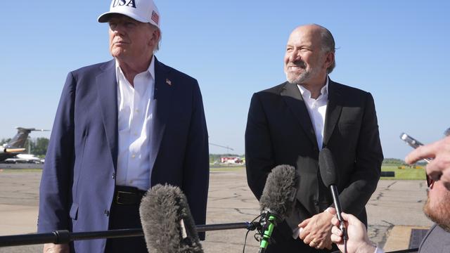 President Donald Trump, left, listens as Commerce Secretary Howard Lutnick speaks with reporters before boarding Air Force One at Morristown Municipal Airport in Morristown, N.J., Sunday, July 6, 2025, en route to Washington. (AP Photo/Jacquelyn Martin)