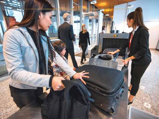 A woman preparing her luggage to go through the security scanner at the airport.