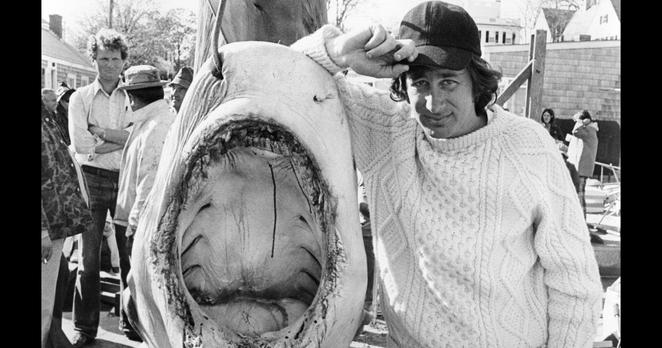 Regisseur Steven Spielberg posiert neben einem Hai an einem Angelhaken.