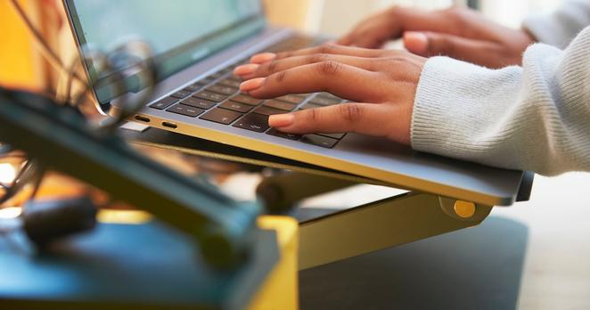 Close up of a pair of hands typing on a laptop keyboard.