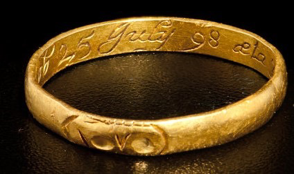 The gold ring inverted to show the text inscribed inside.