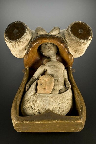 A wooden torso with a cloth baby and organs inside. 