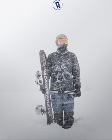 Snowboarder in full gear standing with snowboarder in heavy snowstorm.