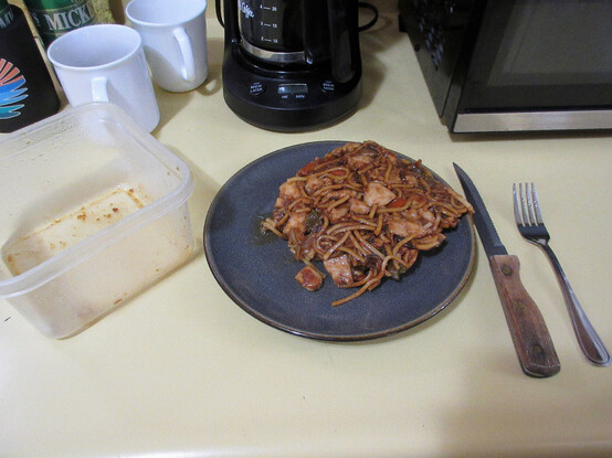 A square plastic container, a square glop of lo mein on a round plate, a knife and fork.
Hovering behind are a beer and koozie, 2 coffee cups, coffee maker, and microwave.
Seems I was having a messy day.