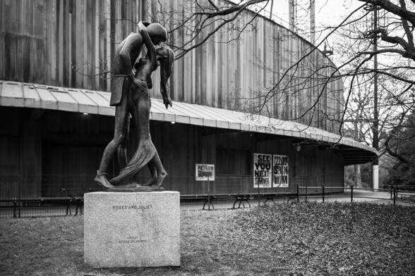 A black and white photo of an outdoor 7 feet (2.1 m) tall bronze sculpture depicting Romeo and Juliet by American artist Milton Hebald, unveiled in 1977 and cast in 1978, located in front of Delacorte Theater.

Central Park, NYC (2023)