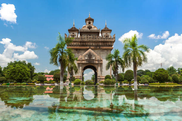 Monumento rodeado de palmeras sobre el agua en Vientiane.