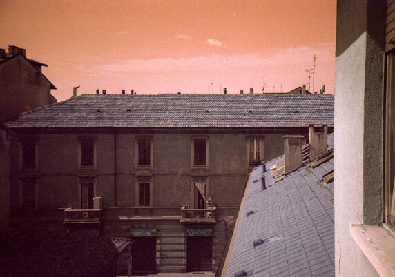An orange sky and buildings seen from a window in some old Italian town. Colours are shifted to orange since the photo was taken with analog Lomography LomoChrome Turquoise 400 35mm film and a Lomography LC-A camera.