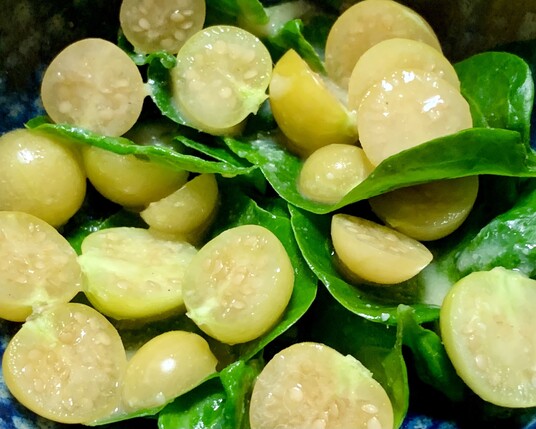 Little yellow berries of Physalis grisea, sliced in half in a blue bowl with vibrant green sissoo leaves. There is a pale white dressing on the salad. 

When physalis berries’ husks turn papery or fall off the stem, the berries might still be a little green. They will ripen to bright yellow on the counter. Leave the husks on until ready to eat. 