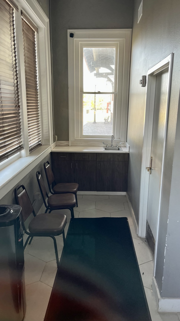 Tiny room with 3 metal chairs, and a sink at the far end