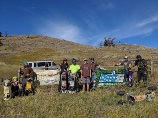group photo of the riders at the Montana big run mountainboard downhill rally. with event banner, mountain, and big blue sky in the background.