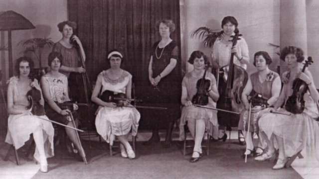 Lina Drechsler Adamson, center, with eight women students at the Toronto Conservatory of Music (six of the women are seated with violins; two of the women are standing with larger string instruments)