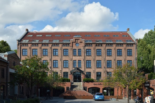 A photo of a brick building with a blue sky with white clouds behind it.
